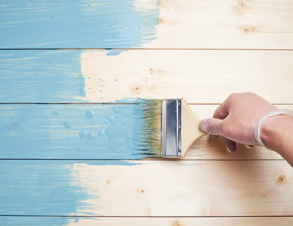 A worker painting wooden surface with a brush