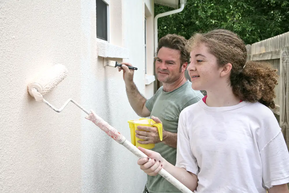 father and daughter painting their house