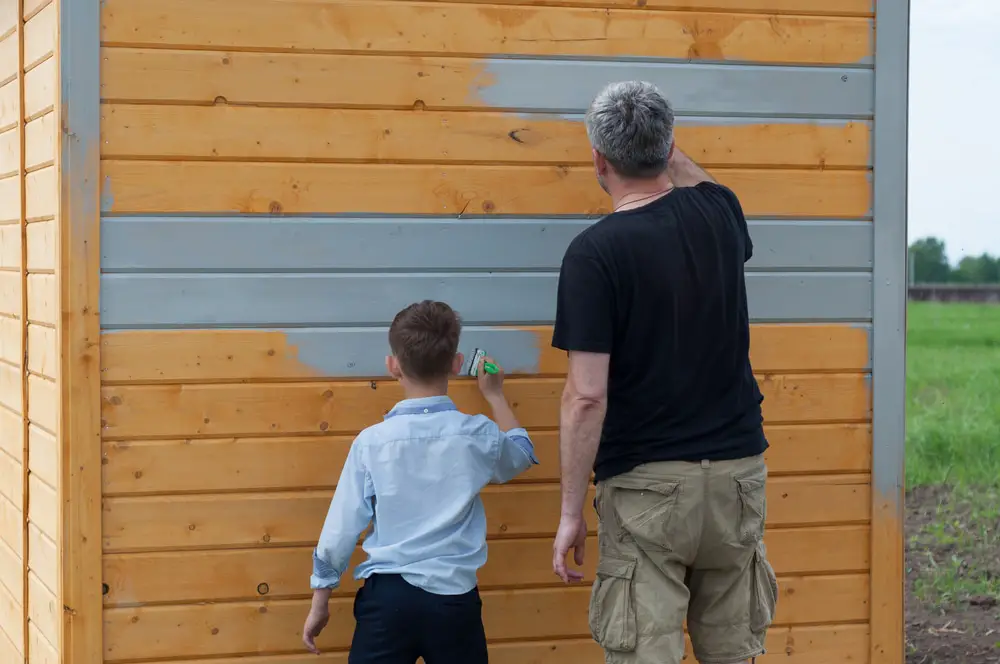 Gray paint is being painted by a father and son.