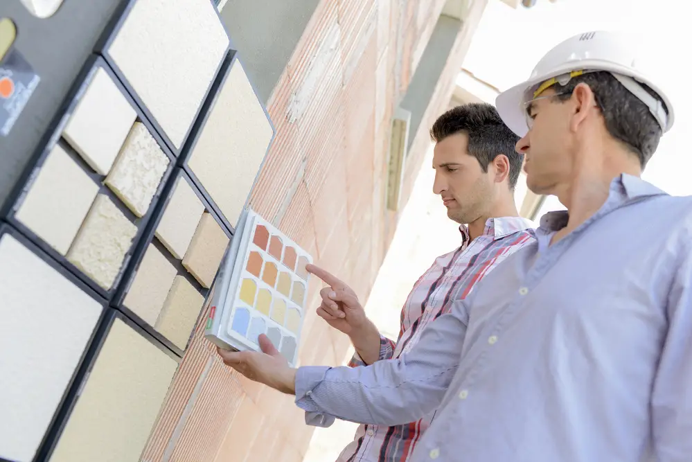 Two men matching colour samples on exterior wall