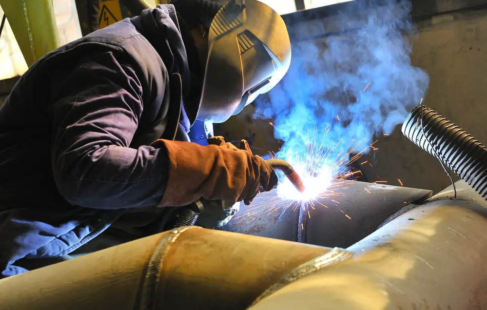 A man cutting metal while wearing protective gears