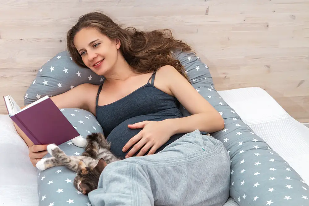 A pregnant woman reading a book in bed