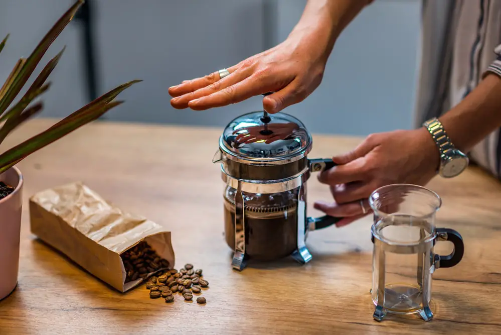 A woman makes coffee in a French press