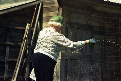 An elderly lady spraying chemicals in her yard