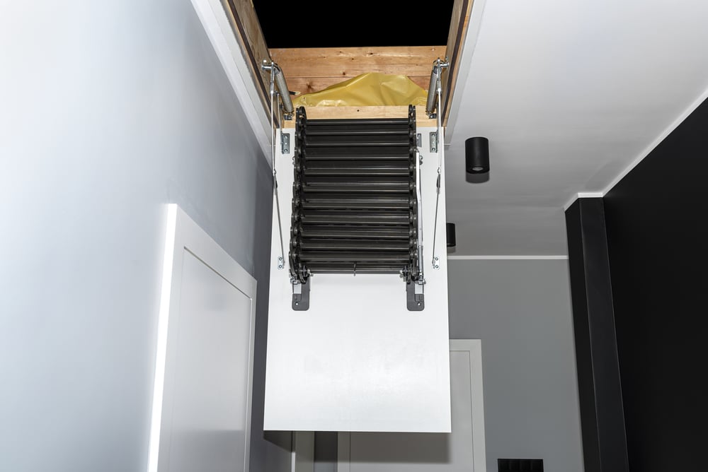 Folding metal stairs to the attic in the ceiling, open hatch and complex stairs, modern look.